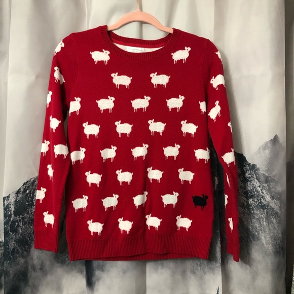 red sweater with white sheep and one black sheep